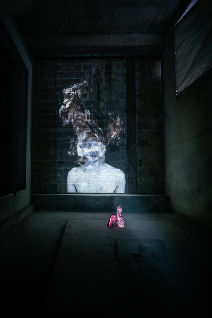 A surreal projection of a ghostly figure illuminating a dimly lit, industrial room.