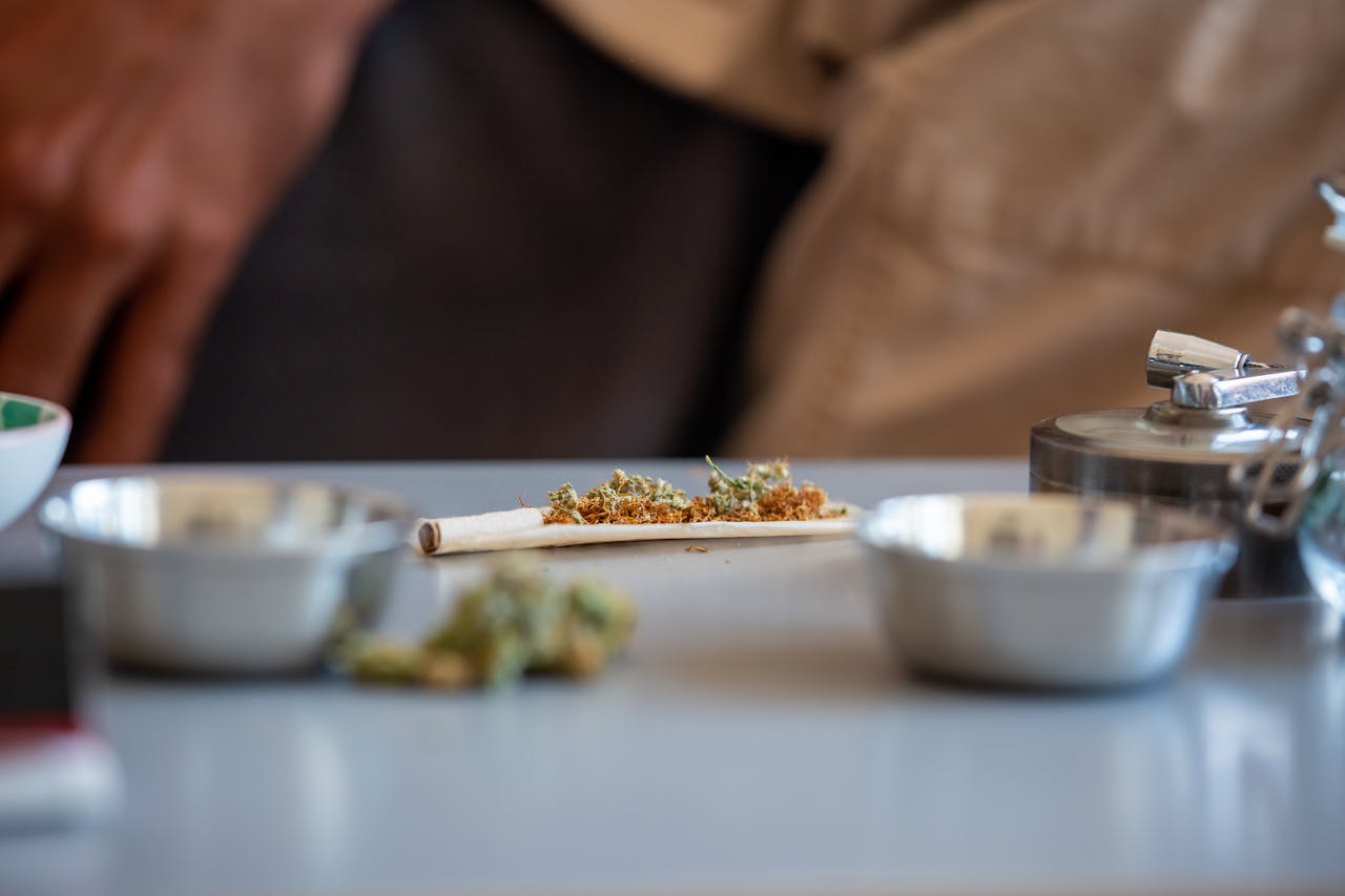 about-01 Detailed close-up of cannabis being rolled into a joint on a table with craft supplies.